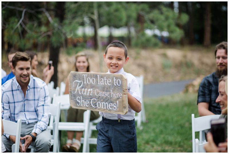 Ring bearer walking down aisle with sign