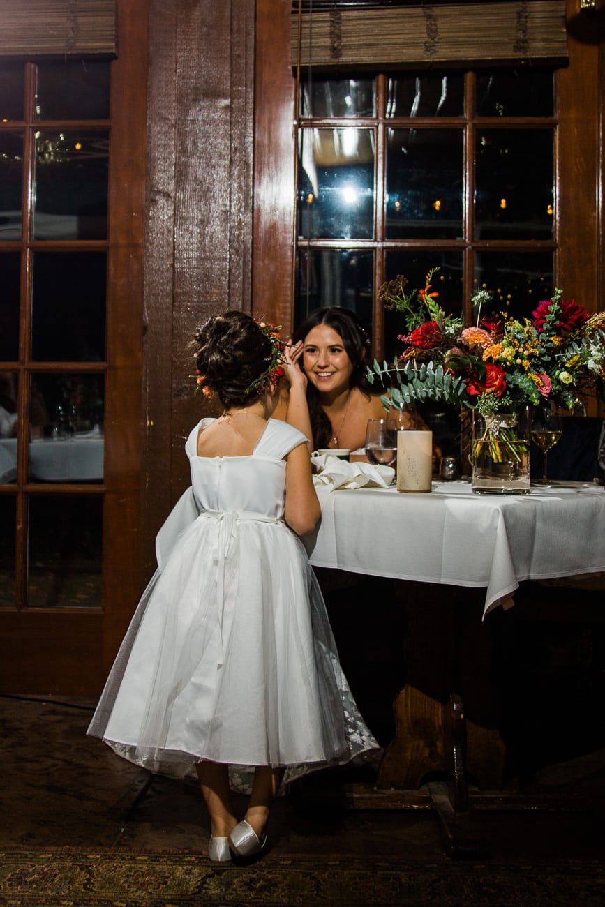 Bride and flower girl talking at dinner