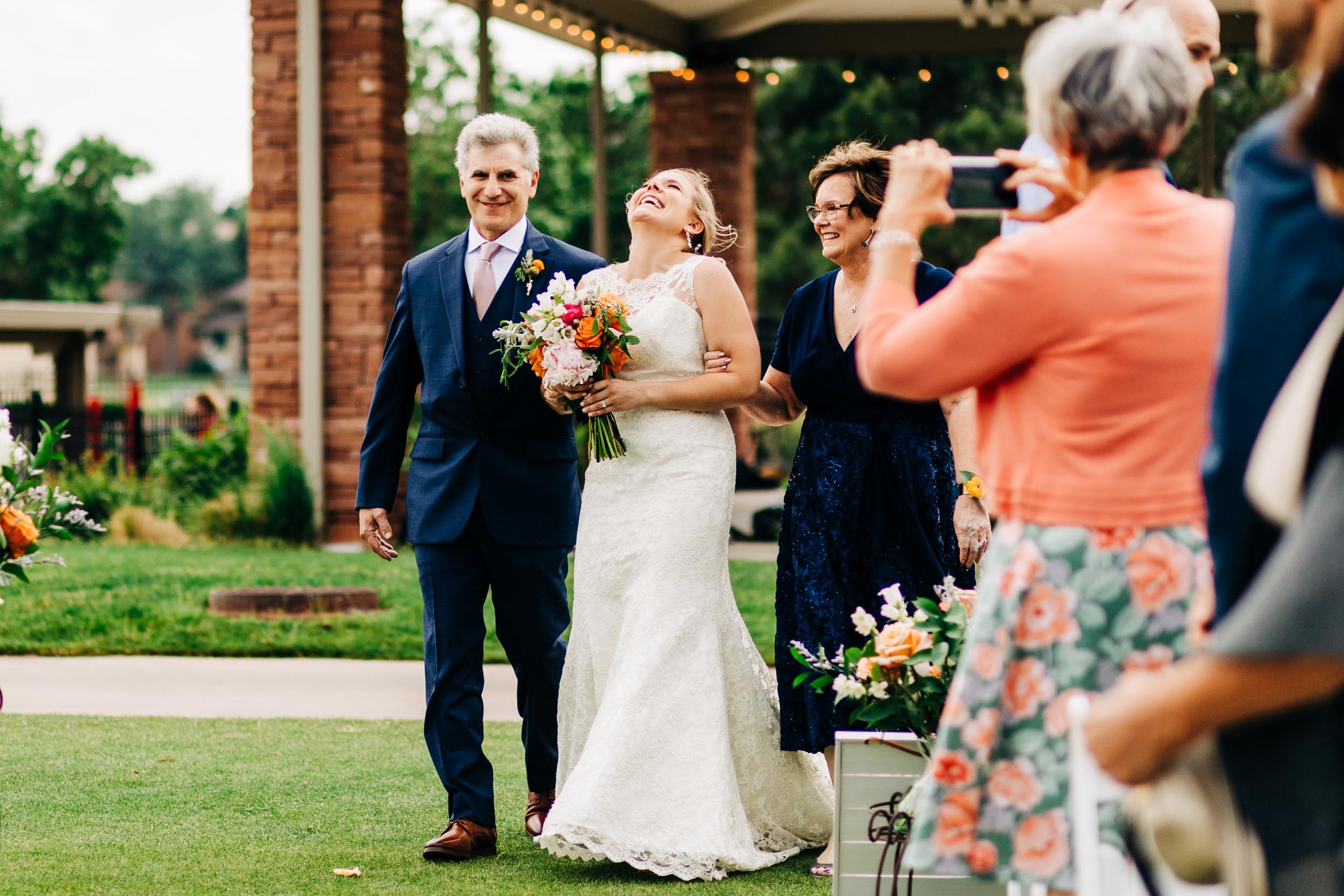 bride throwing her head back laughing while walking down the aisle by Shea McGrath Photography Denver Colorado Wedding Photographer