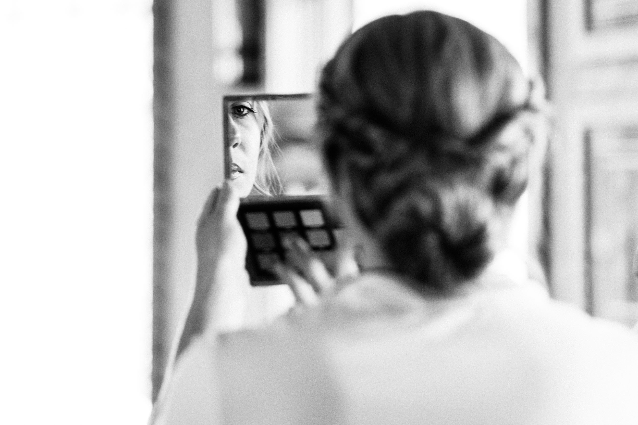 Bride looking in mirror at makeup