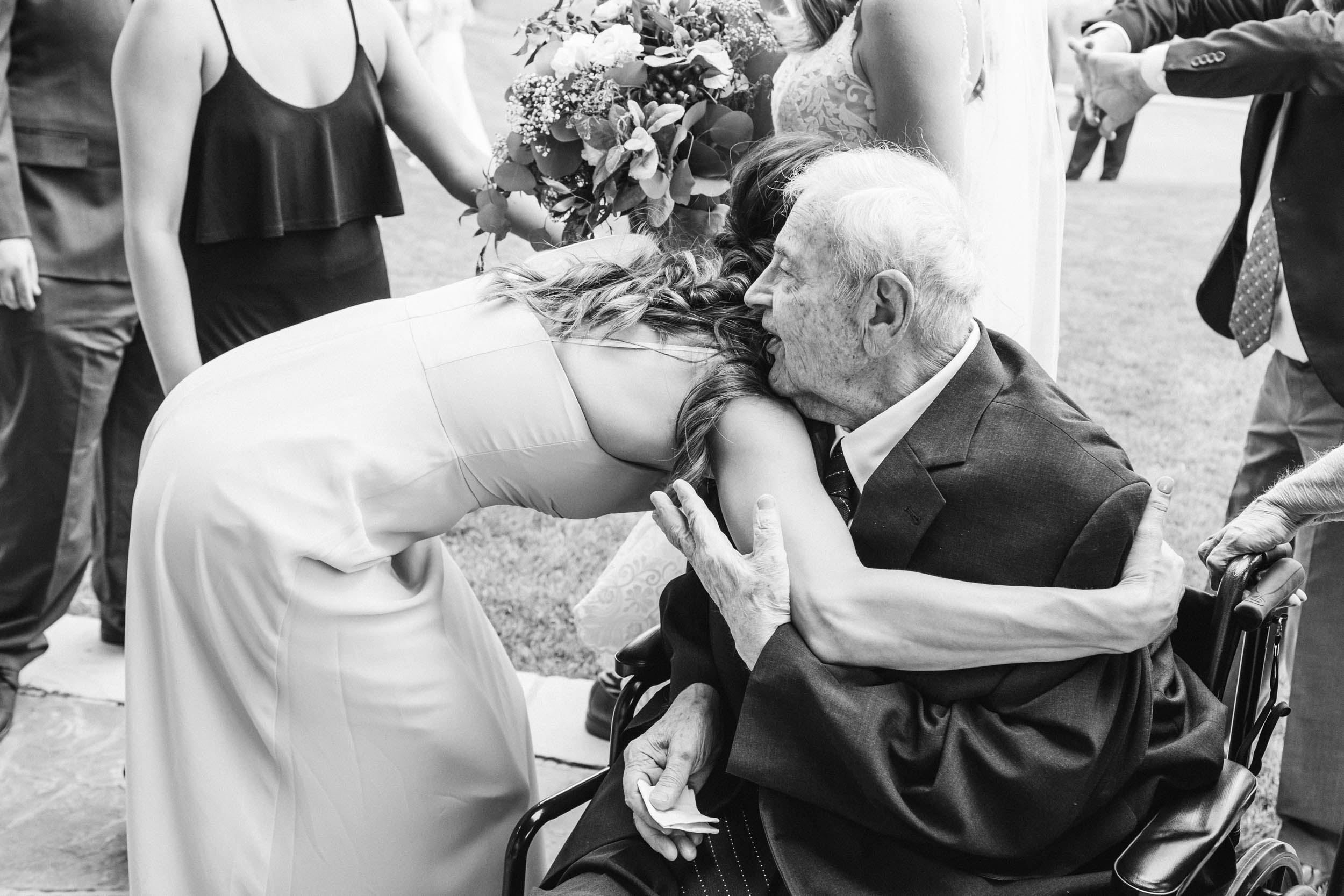 bridesmaid hugging grandfather at wedding