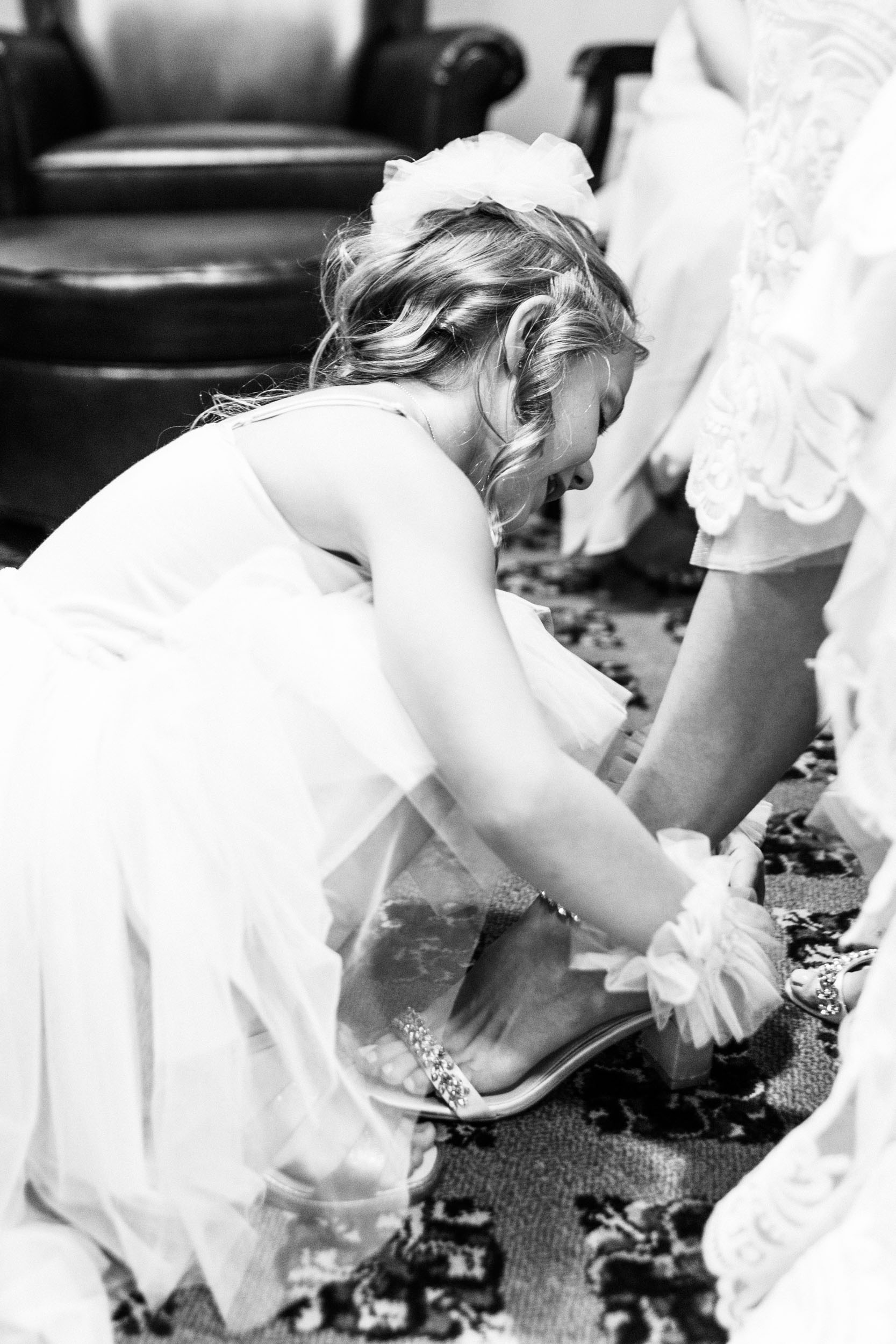 flower girl putting on bride's shoe