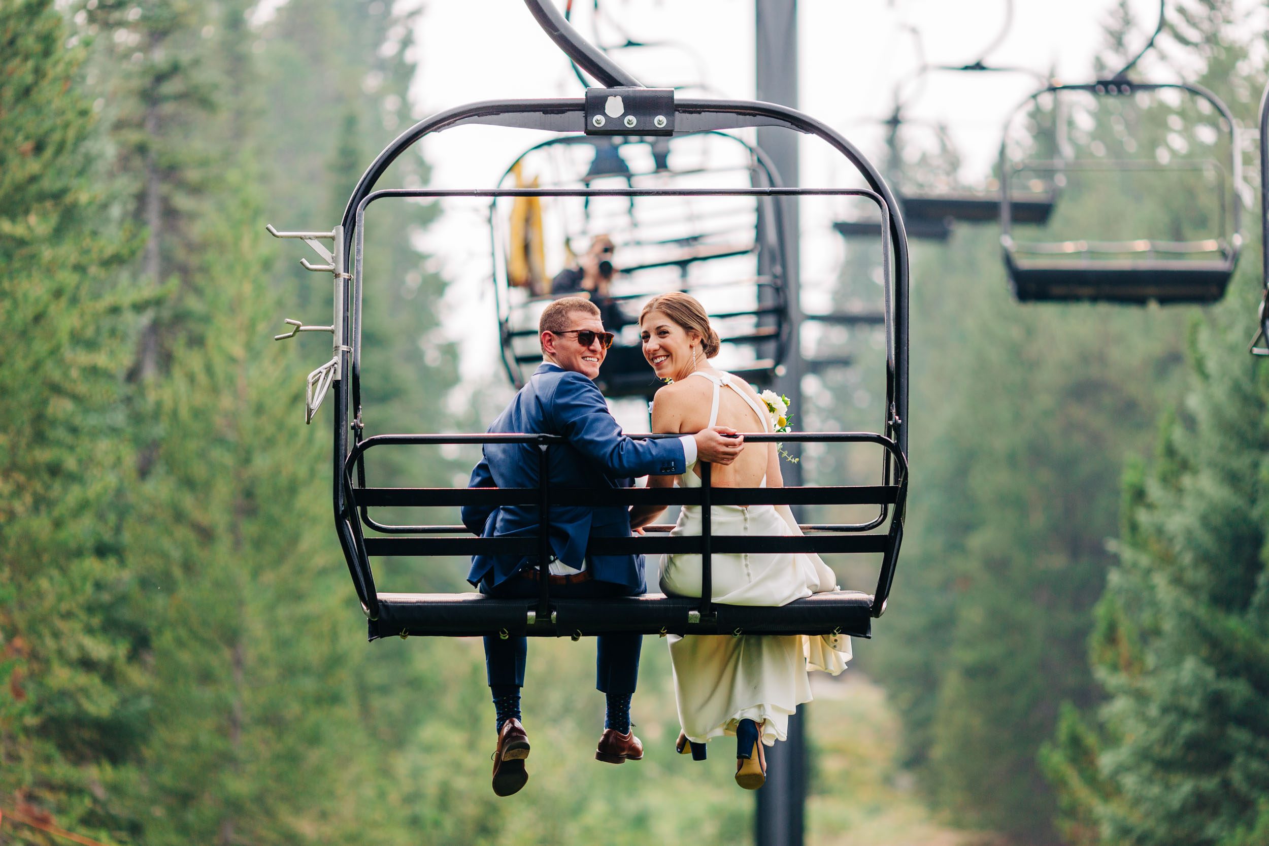 Bride and groom riding ski lift at winter park resort