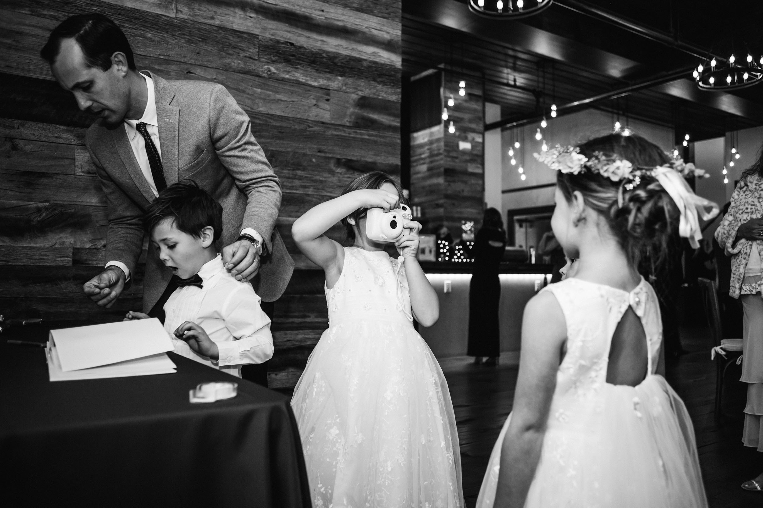 flower girls taking pictures at guest book table