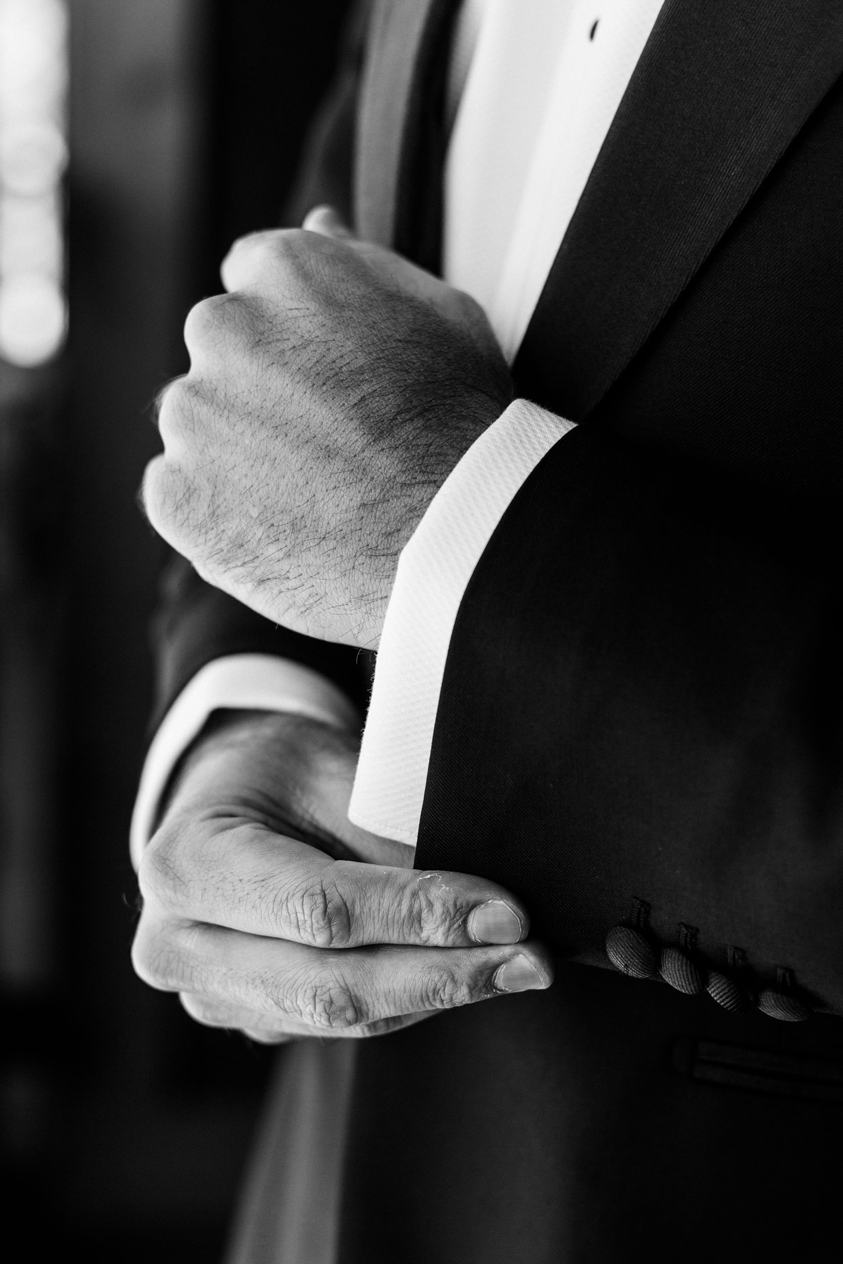detail photo of groom putting on cuff links