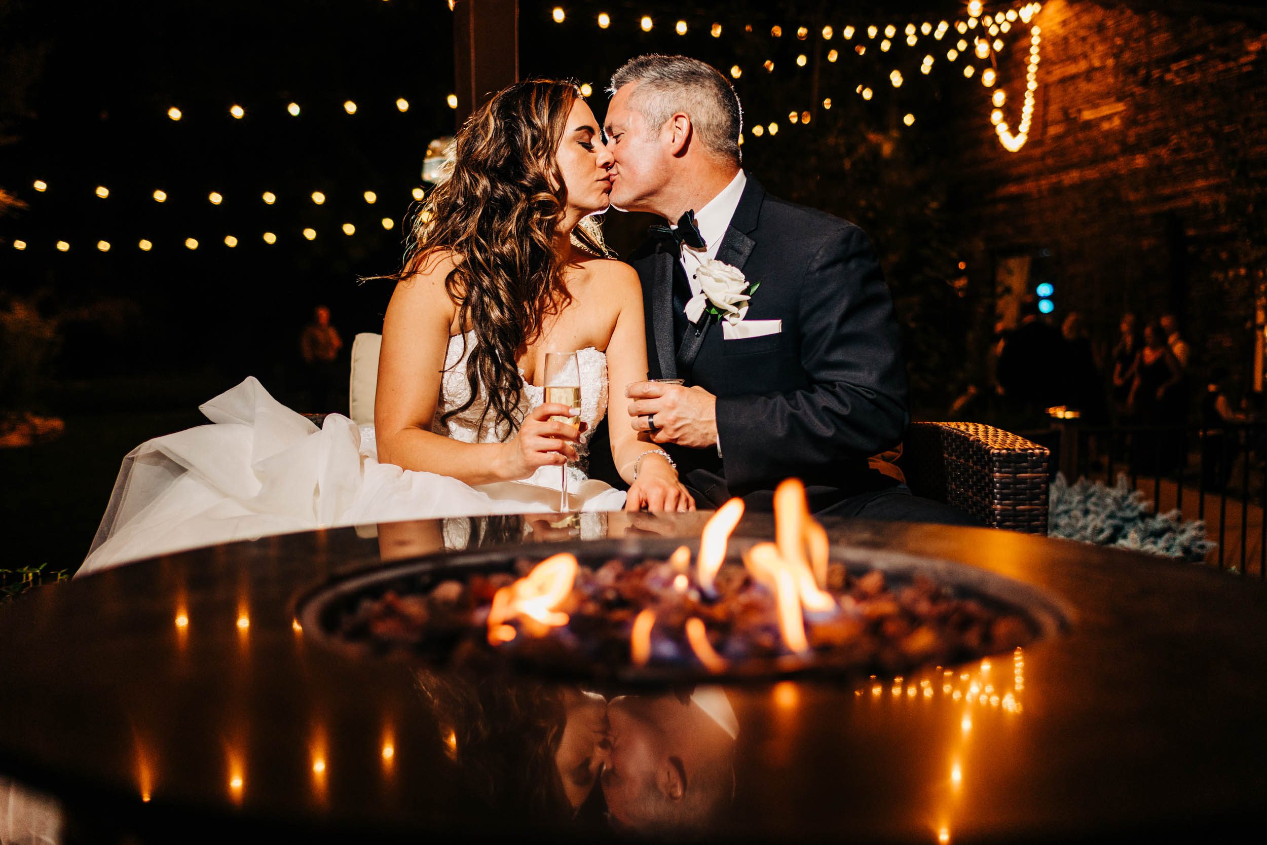photograph of bride and groom kissing by the fire at church ranch event center