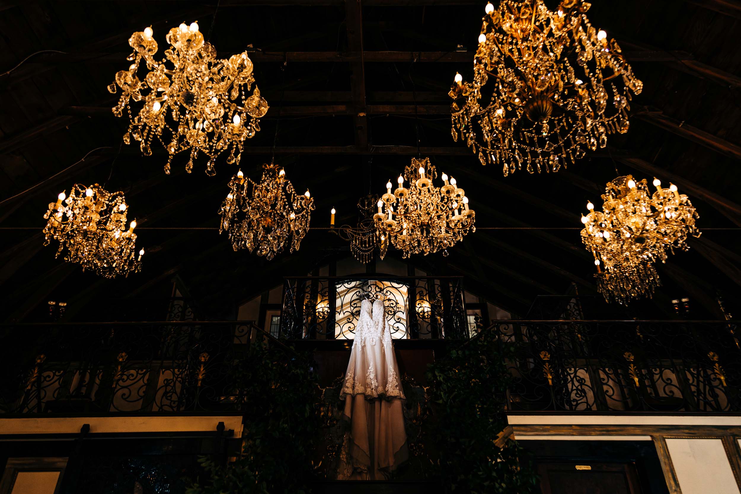 wedding dress hanging in chandelier barn