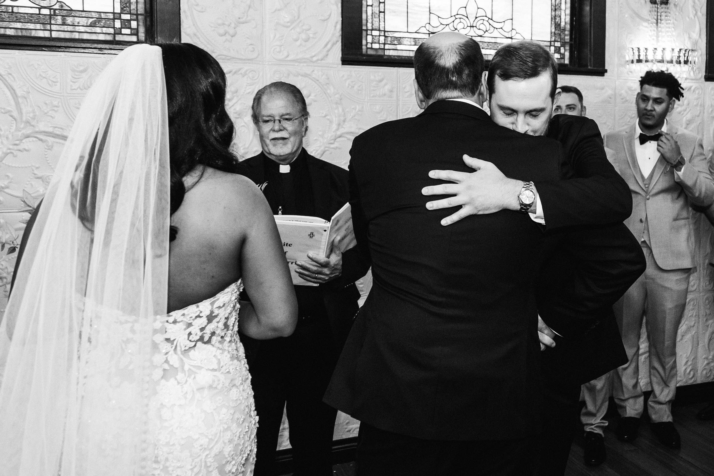 father of the bride and groom hugging at the ceremony