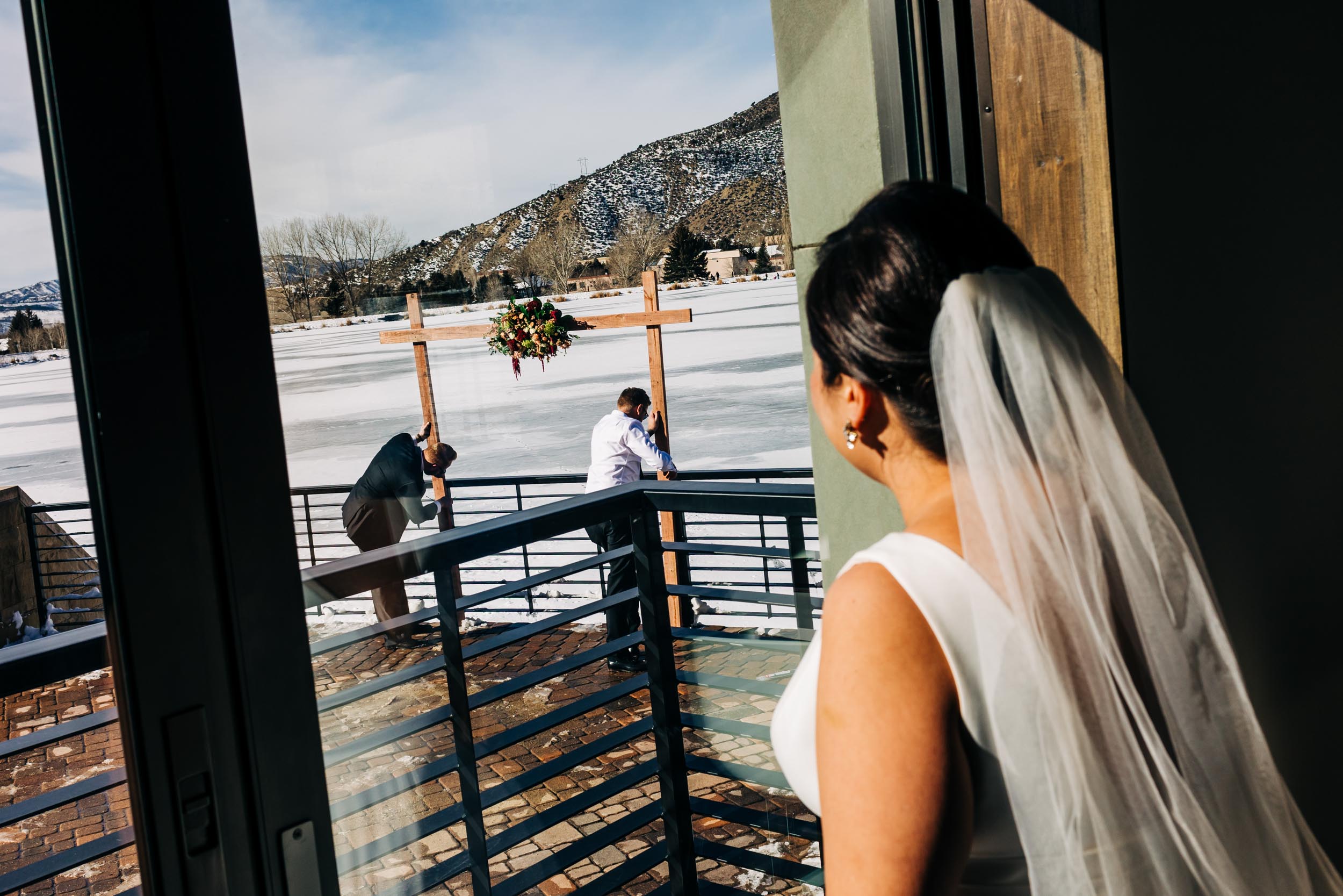 bride watching groom build wedding arbor from inside
