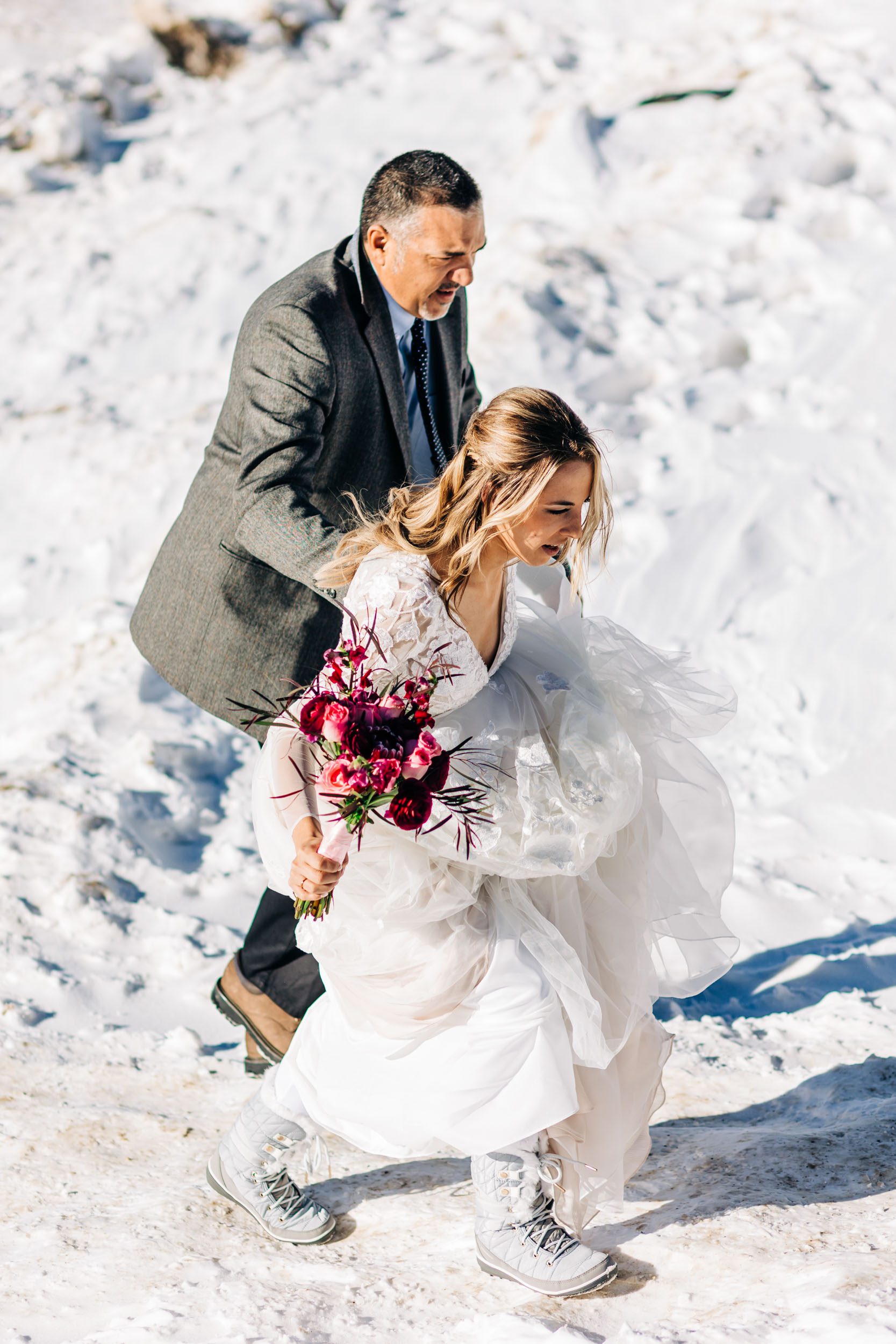 bride and father walking up snowy hill for first look