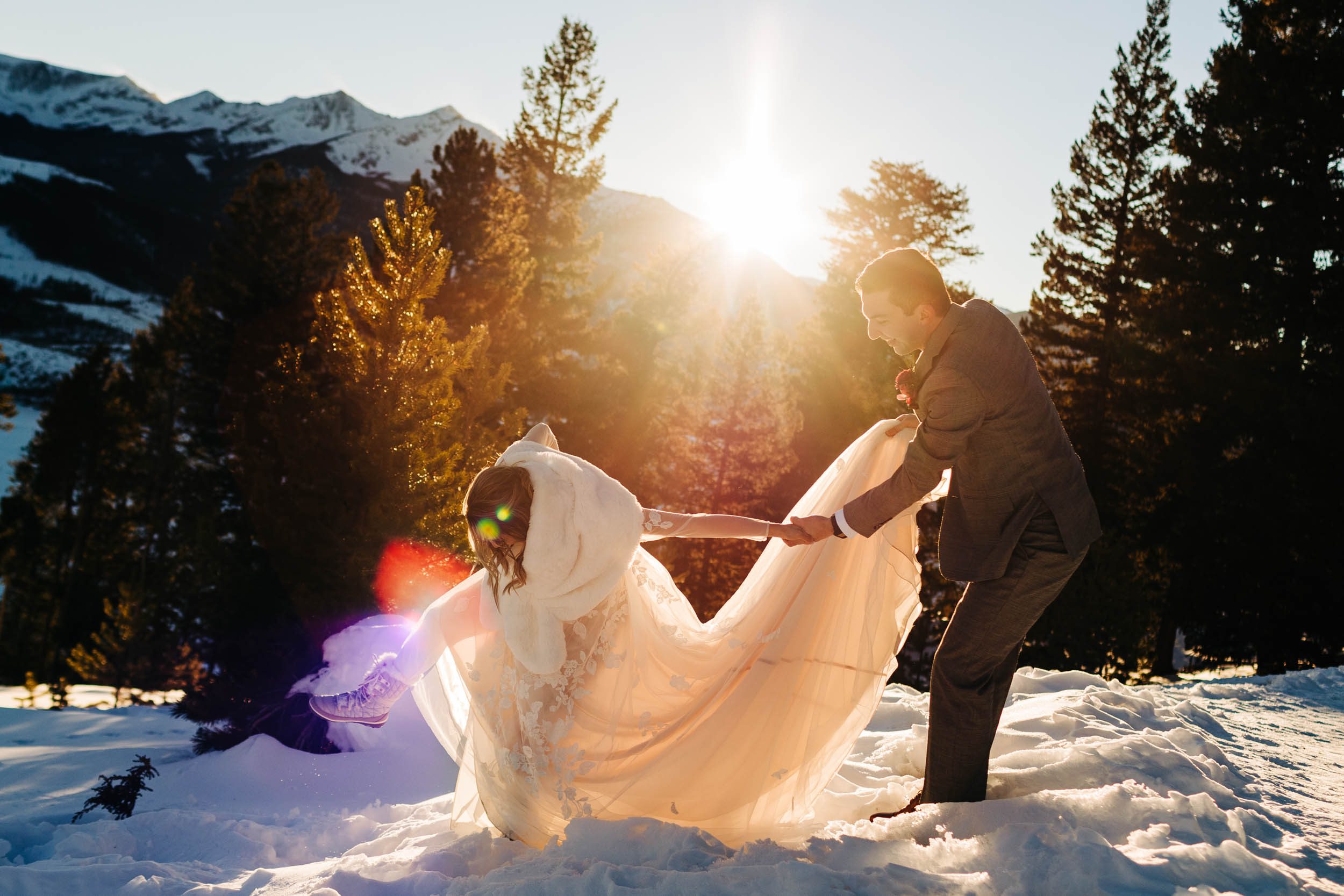 bride almost falling in the snow while groom holds her hand